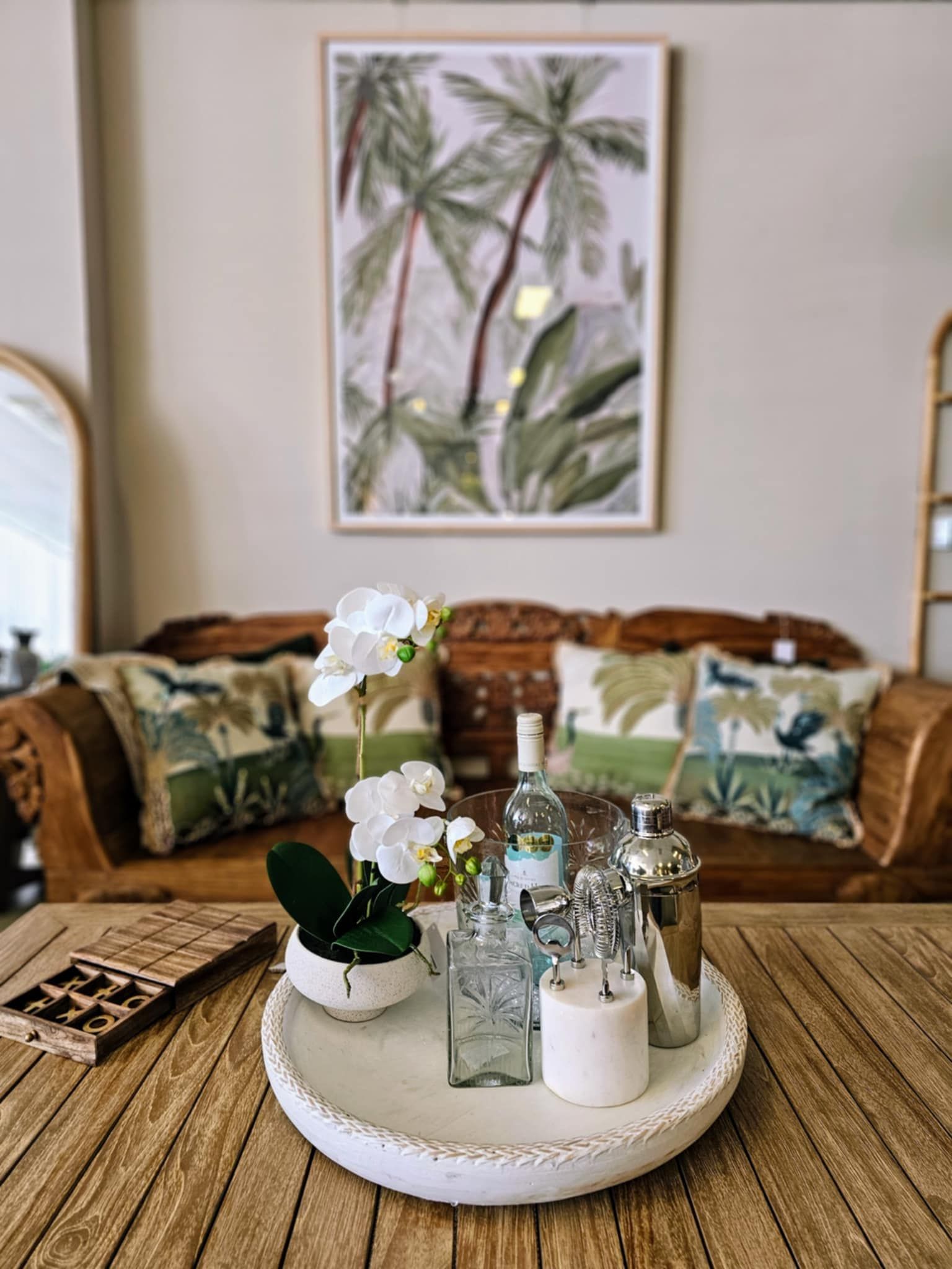 Wooden Table with Decor in Front of A Wood Couch with Pillows and Palm Art — Tropic Living in Mossman, QLD