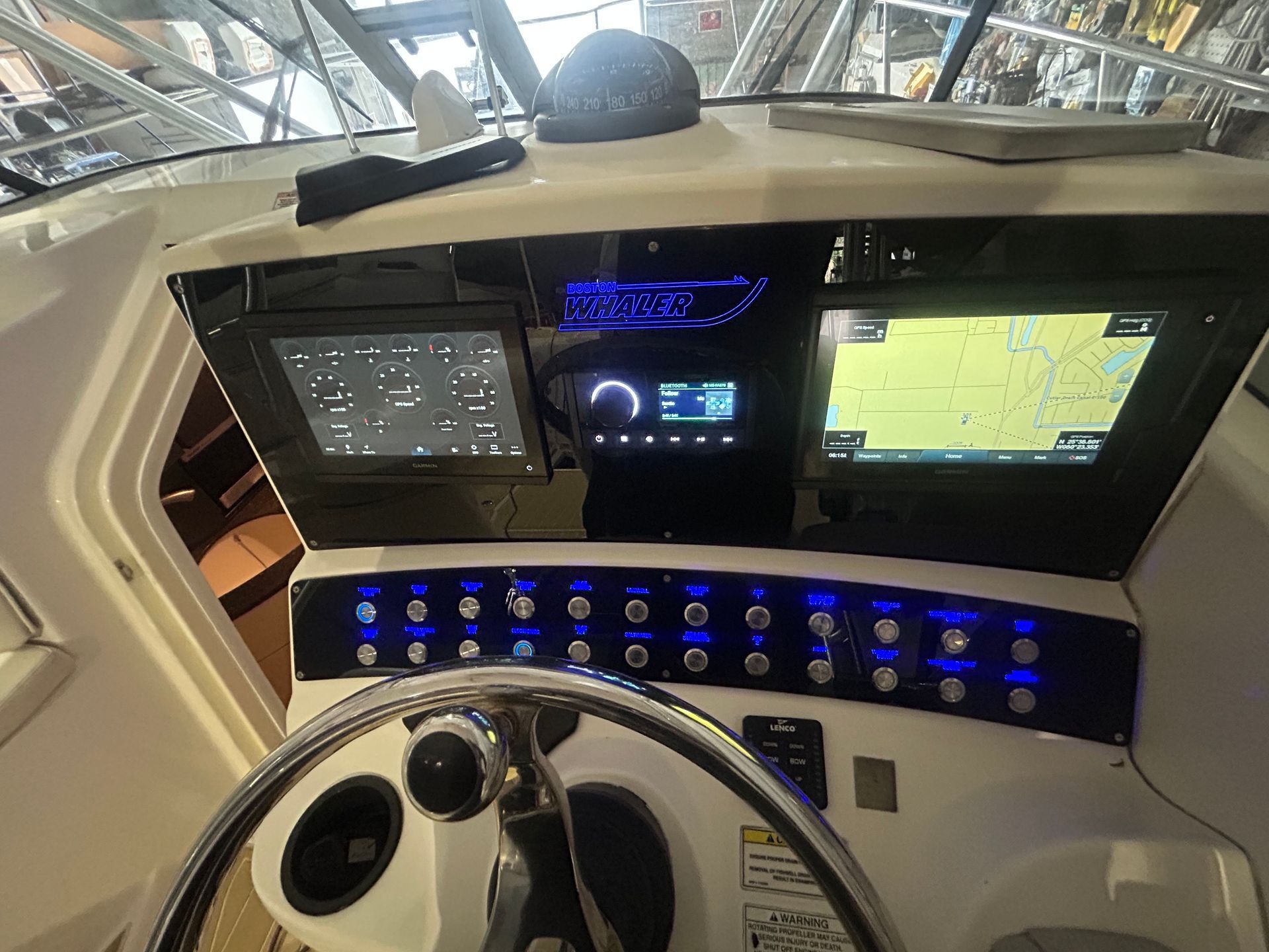 Boat dashboard with screens, buttons, and a steering wheel; displays navigation and controls.