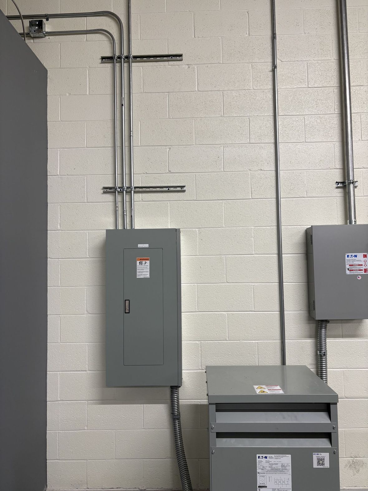 Technician inspecting a wall-mounted solar inverter in a utility room