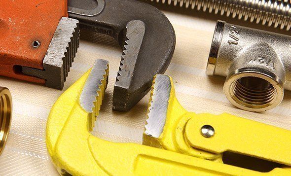 Close-up of plumbing tools, including wrenches and pipe fittings.