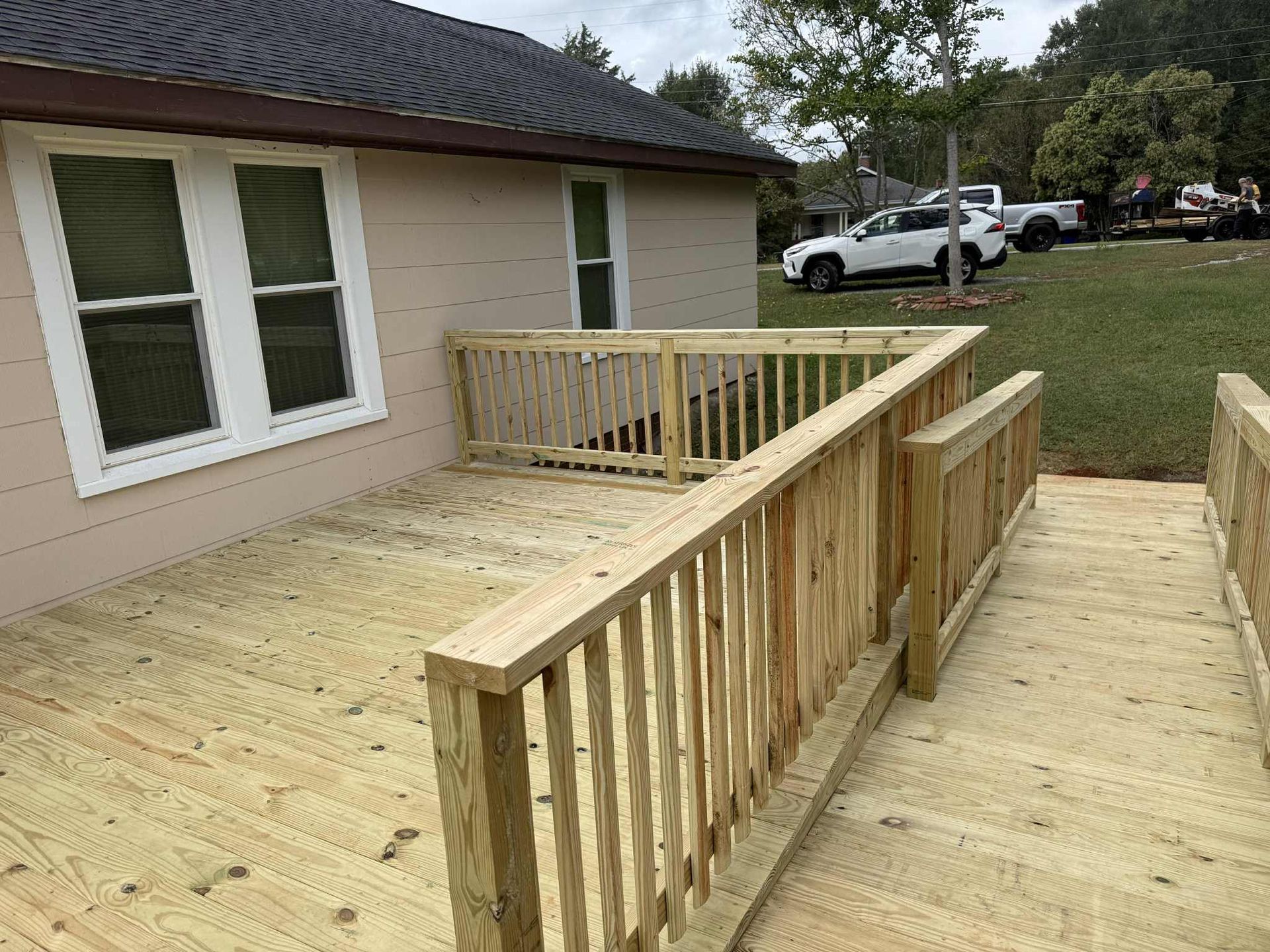 Wooden deck and ramp attached to a light-colored house.