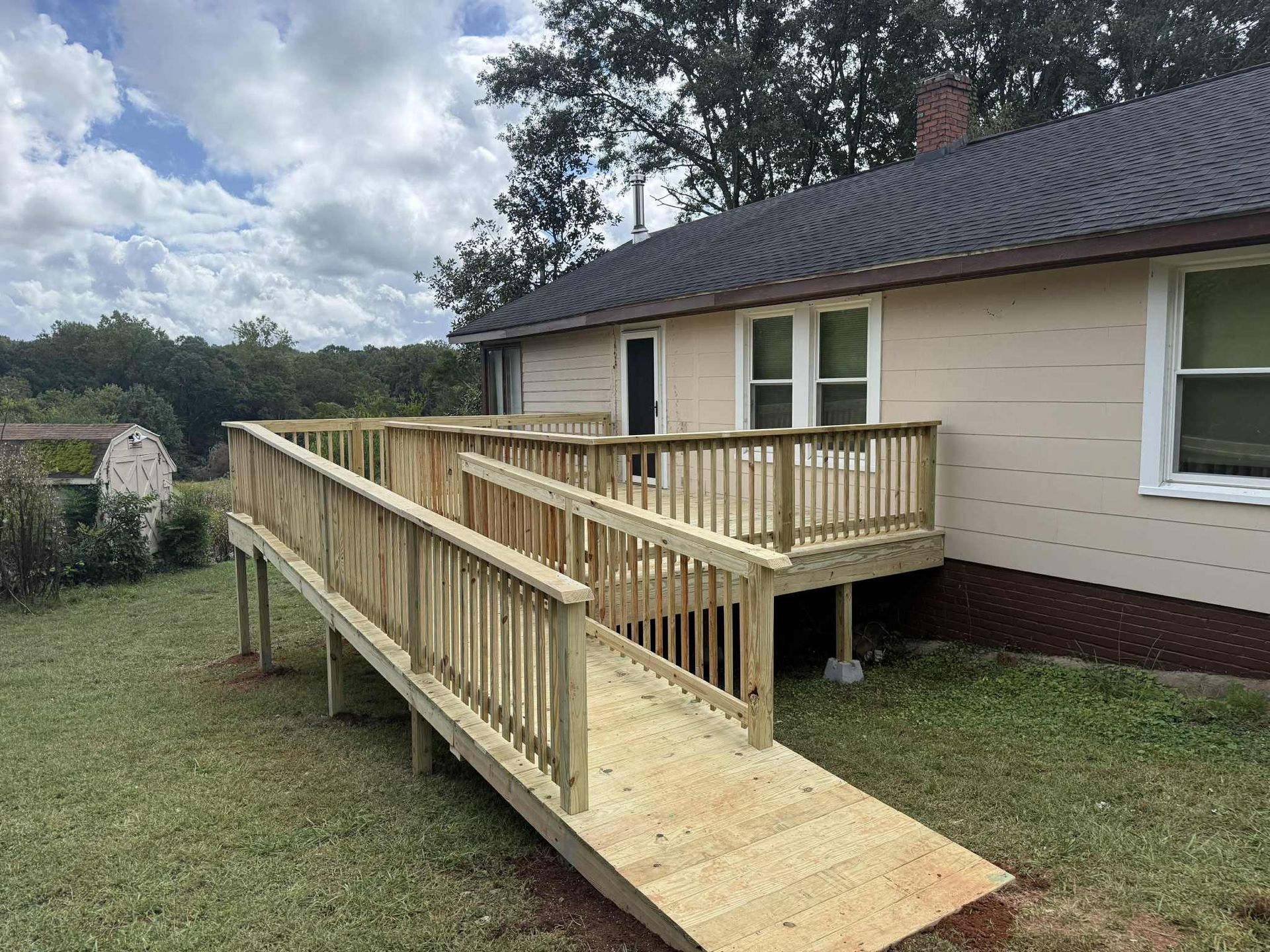 Wooden ramp and deck attached to a light-colored house for accessibility.