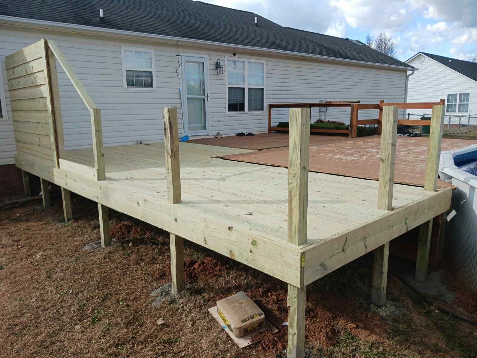 Partially built wooden deck attached to a light-colored house.