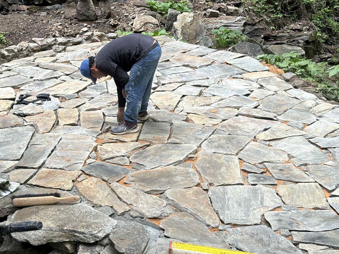 Person laying irregular flagstone patio outdoors.