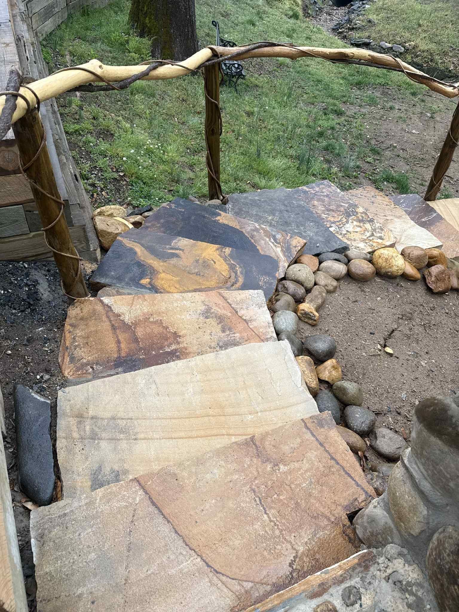 Stone steps with natural wood railing lead downwards, surrounded by rocks and vegetation.