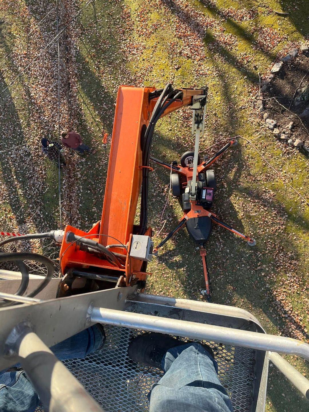 Orange construction drill on a steel platform drilling into a grassy area.