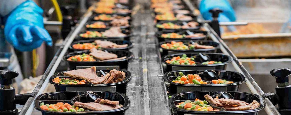 a conveyor belt filled with containers of food in a factory .
