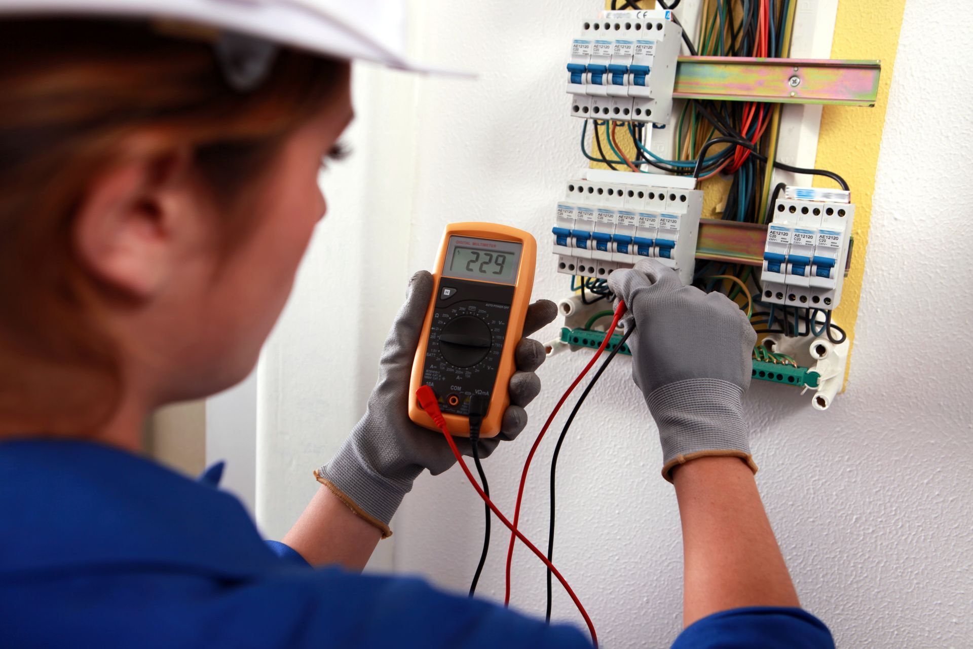 a woman is using a multimeter to check a circuit board