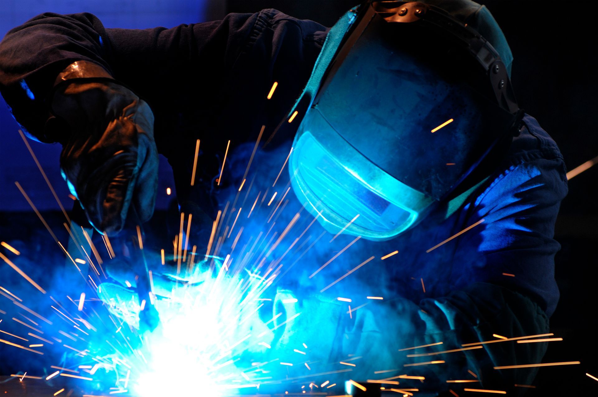 a man wearing a welding mask is welding a piece of metal