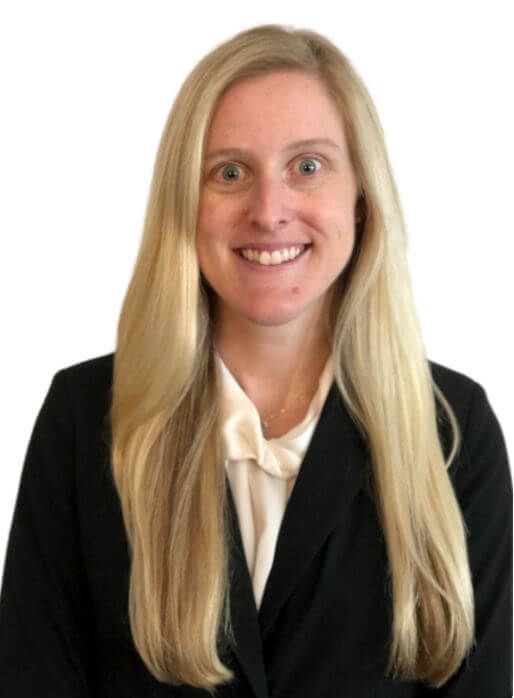 Woman with long blonde hair, smiling, wearing a black blazer and white blouse.