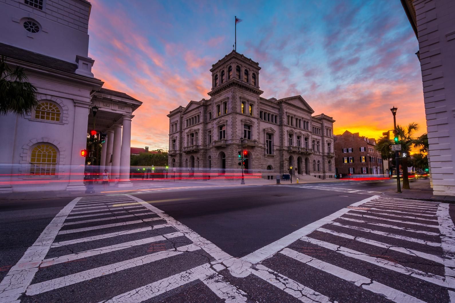 Buildings at intersection at dusk with colorful sky and street markings.