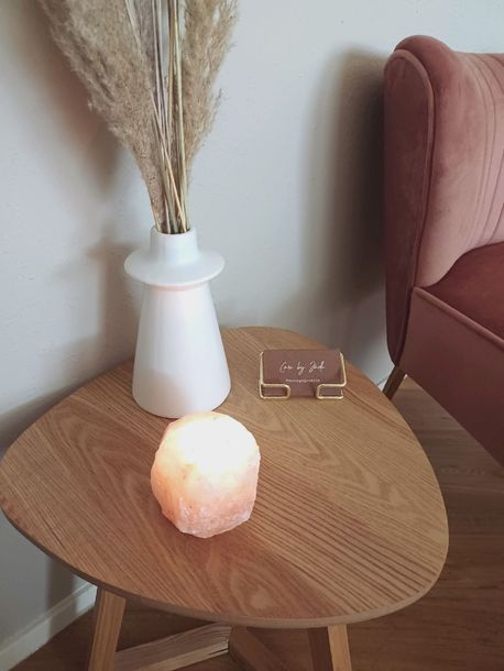 Een houten tafel met een kaars en een vaas met bloemen erop.