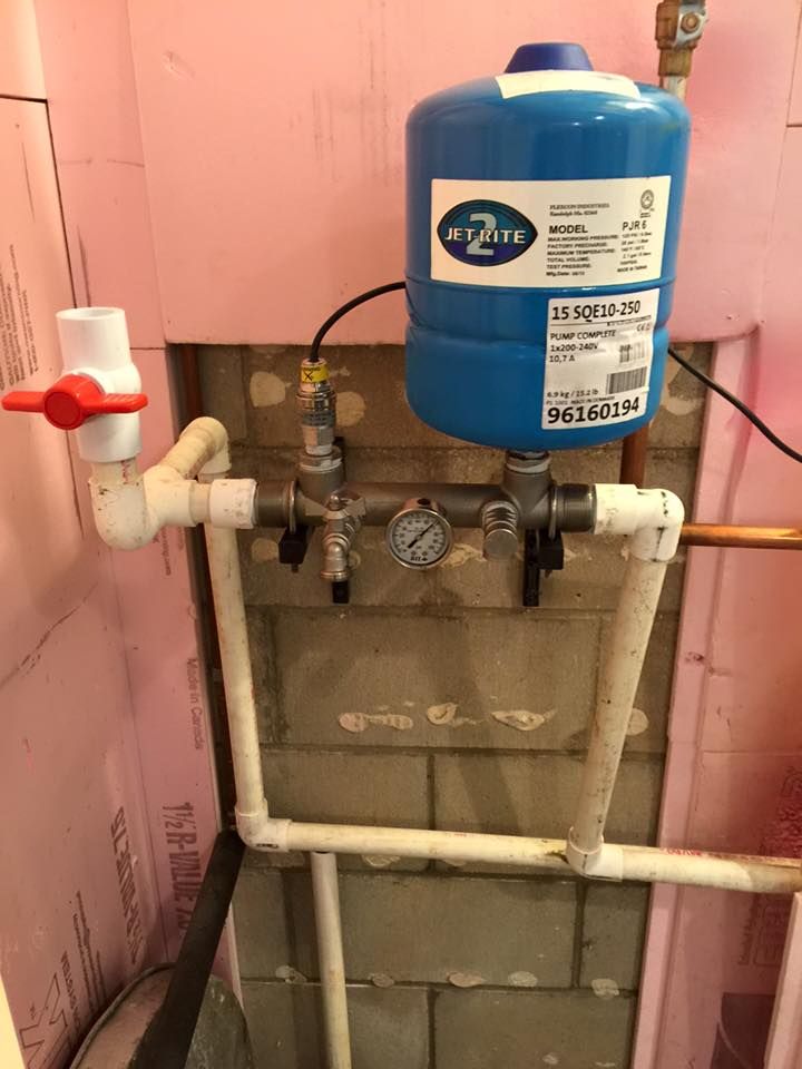 A blue water tank is attached to a pipe in a room.