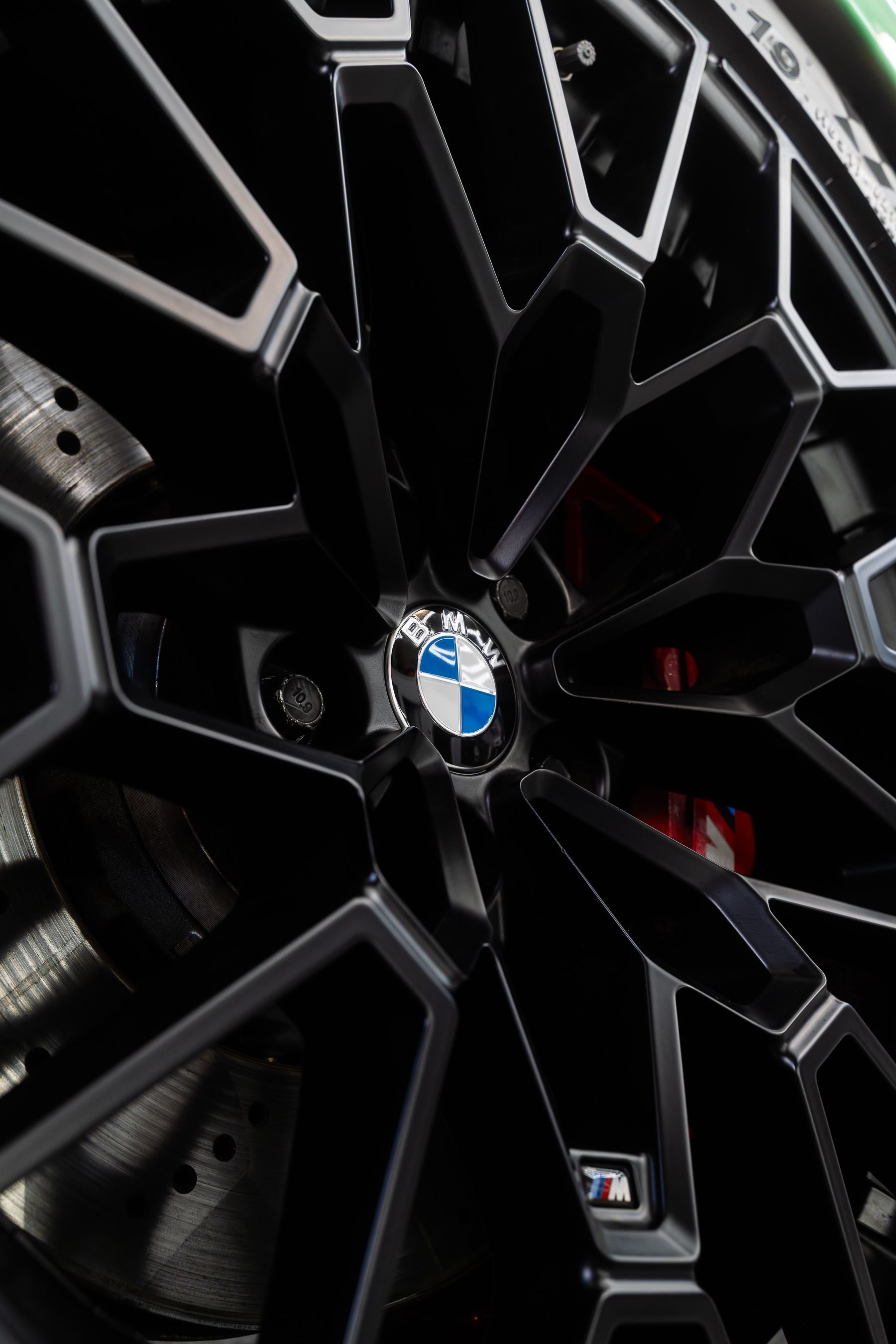 A close-up shot of a black and silver BMW alloy wheel with a prominent BMW logo and an M badge on a spoke.