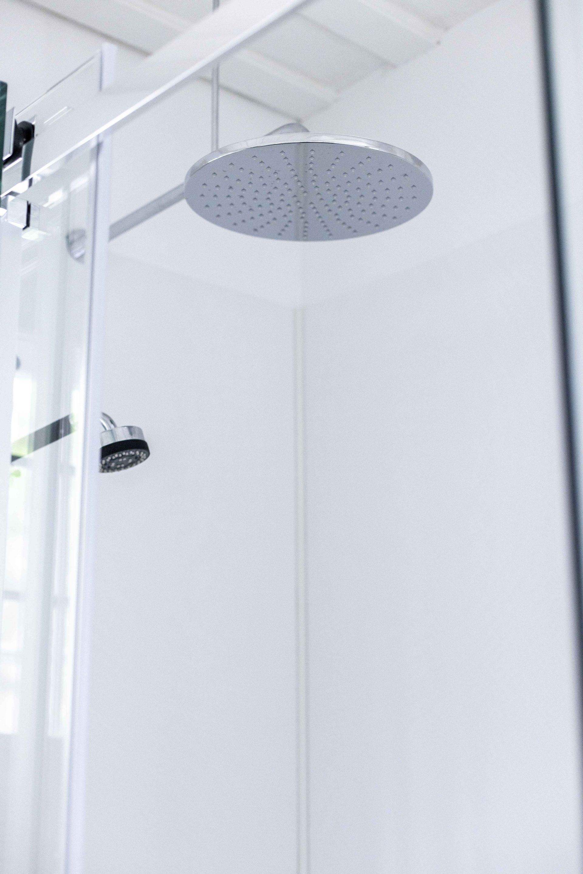 Cabine de douche blanche avec une grande pomme de douche ronde.