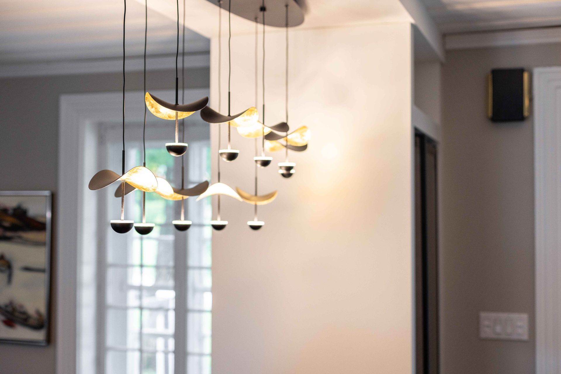 Lustre moderne avec plusieurs suspensions dans une pièce aux murs neutres.