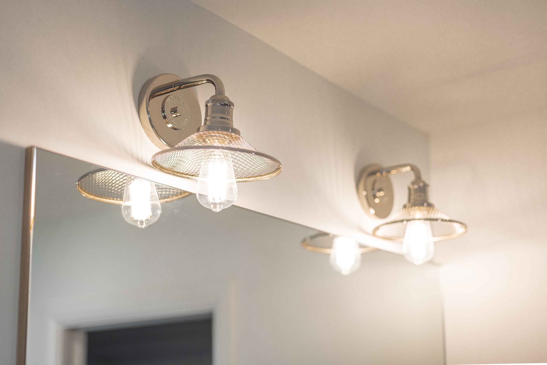 Deux appliques argentées avec ampoules Edison au-dessus d'un miroir de salle de bain.