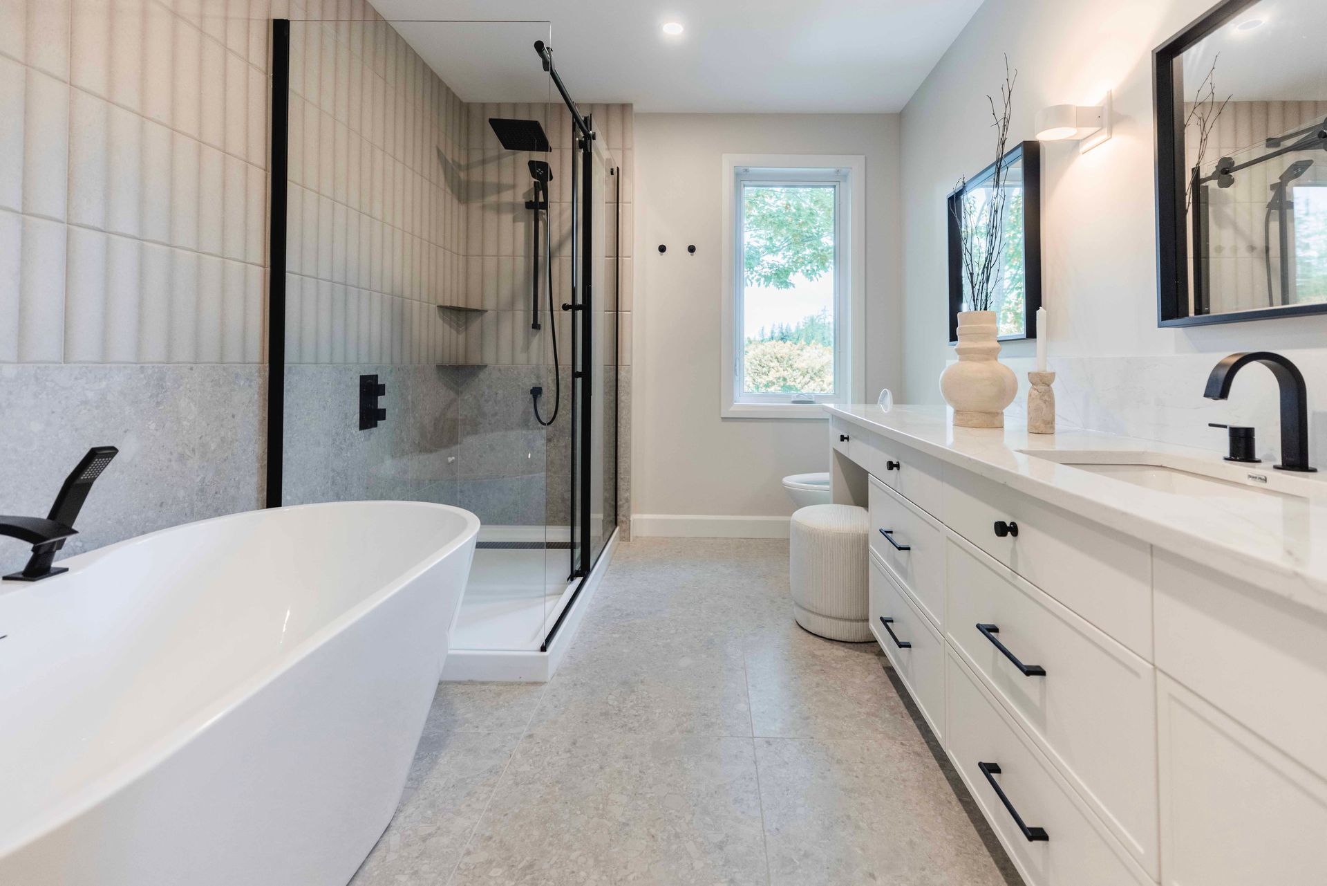 Salle de bains moderne avec baignoire blanche, douche noire et meuble-lavabo blanc.