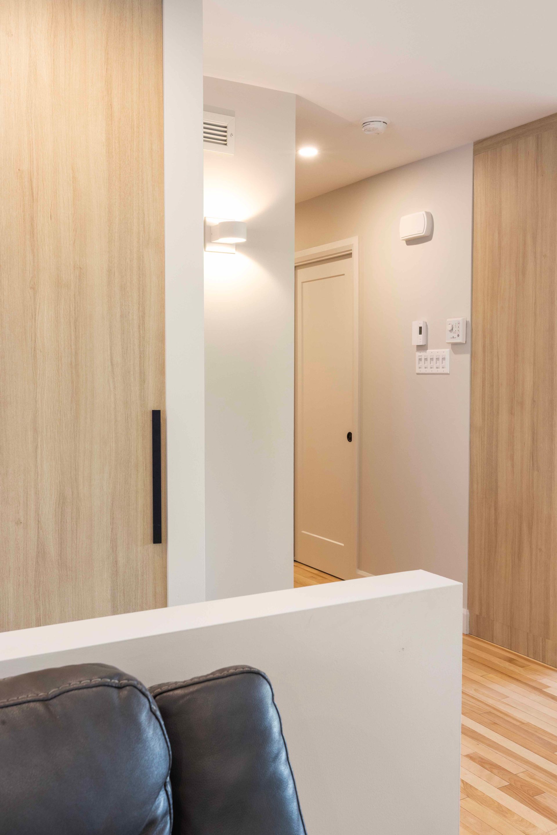 Couloir avec lambris clair et une porte avec une porte blanche fermée.