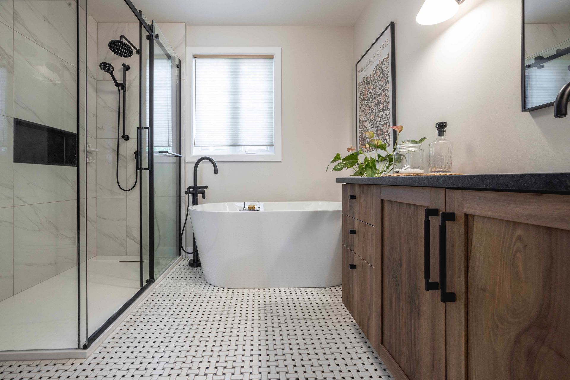 Salle de bains avec baignoire îlot blanche, douche en verre, meuble-lavabo en bois et sol carrelé blanc.