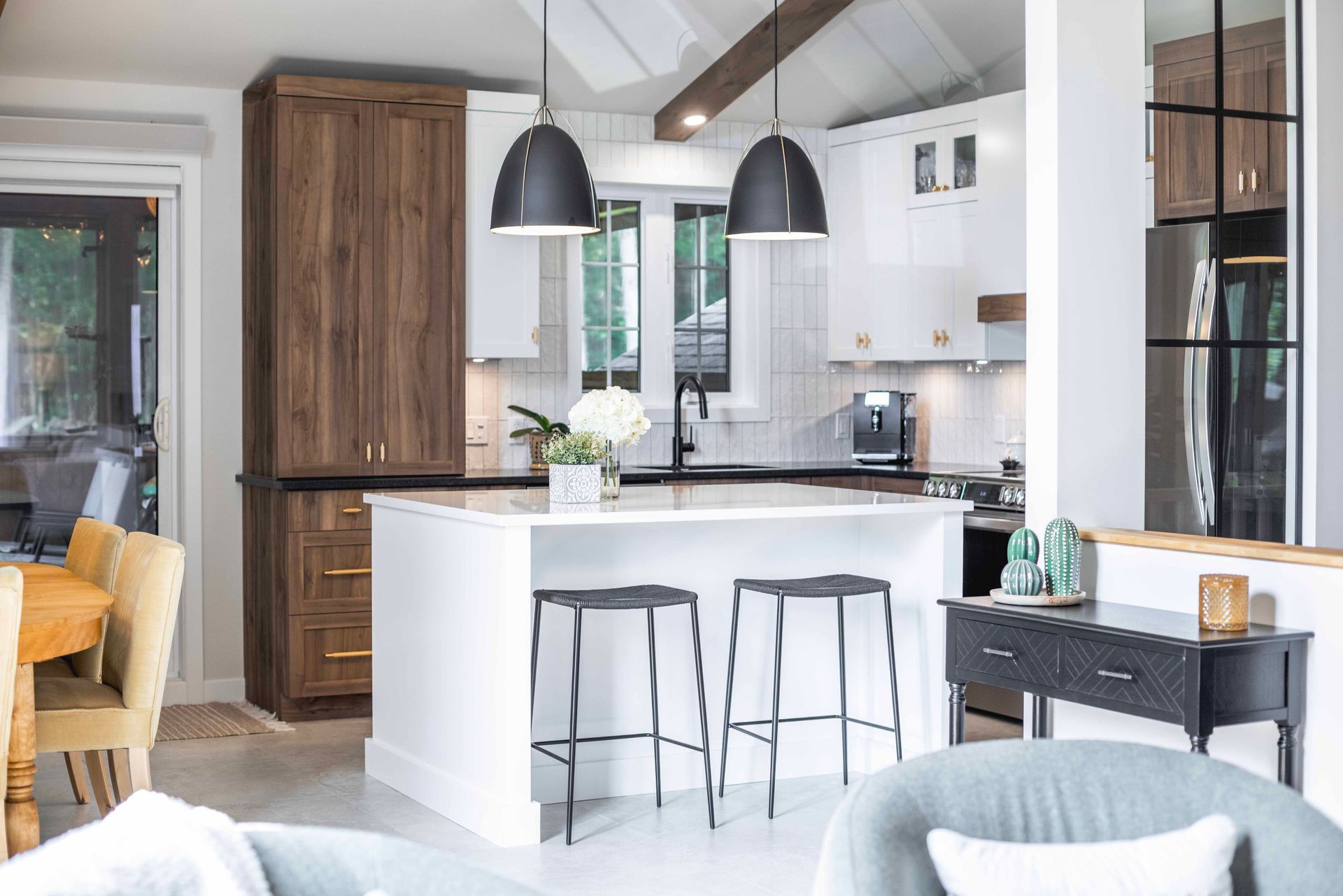 Cuisine moderne avec îlot blanc, suspensions lumineuses noires et placards en bois.
