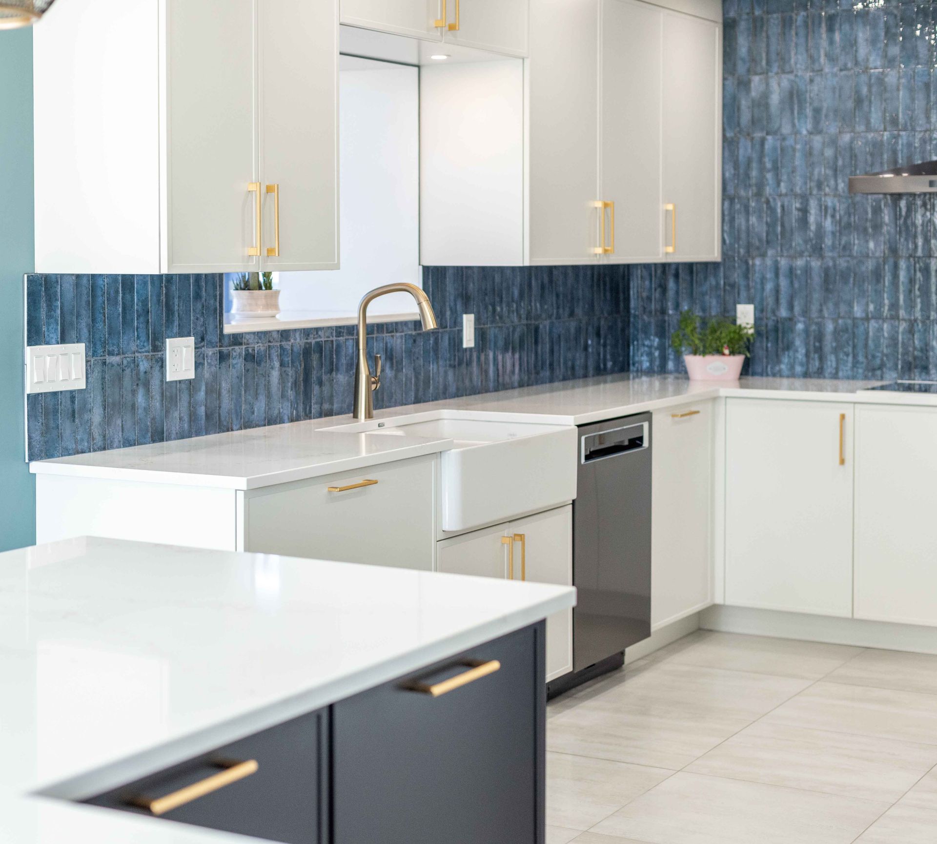 Cuisine moderne blanche avec crédence en carrelage bleu et robinetterie dorée.