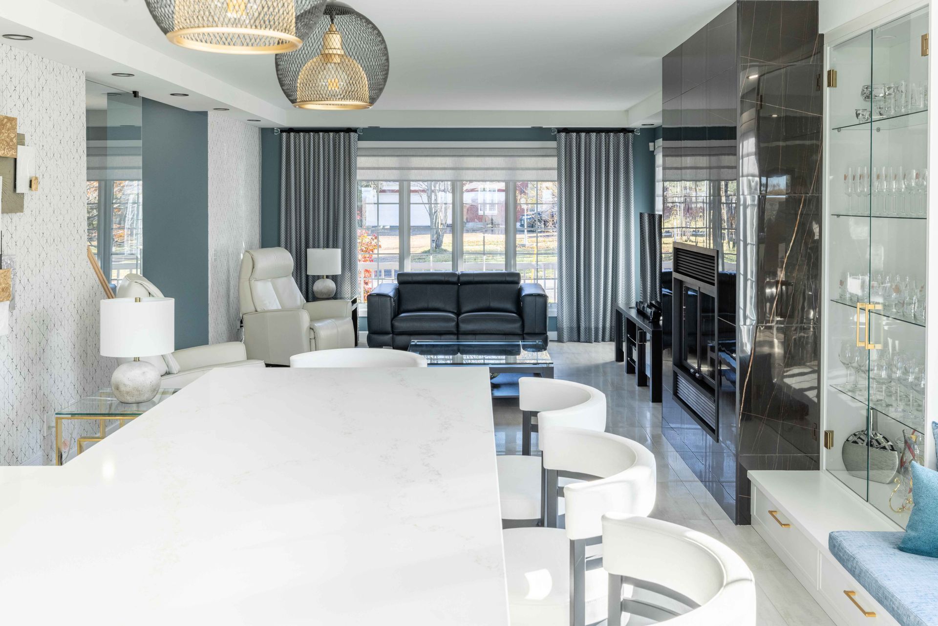 Cuisine et séjour modernes avec un grand îlot blanc, un canapé noir et des touches de bleu.