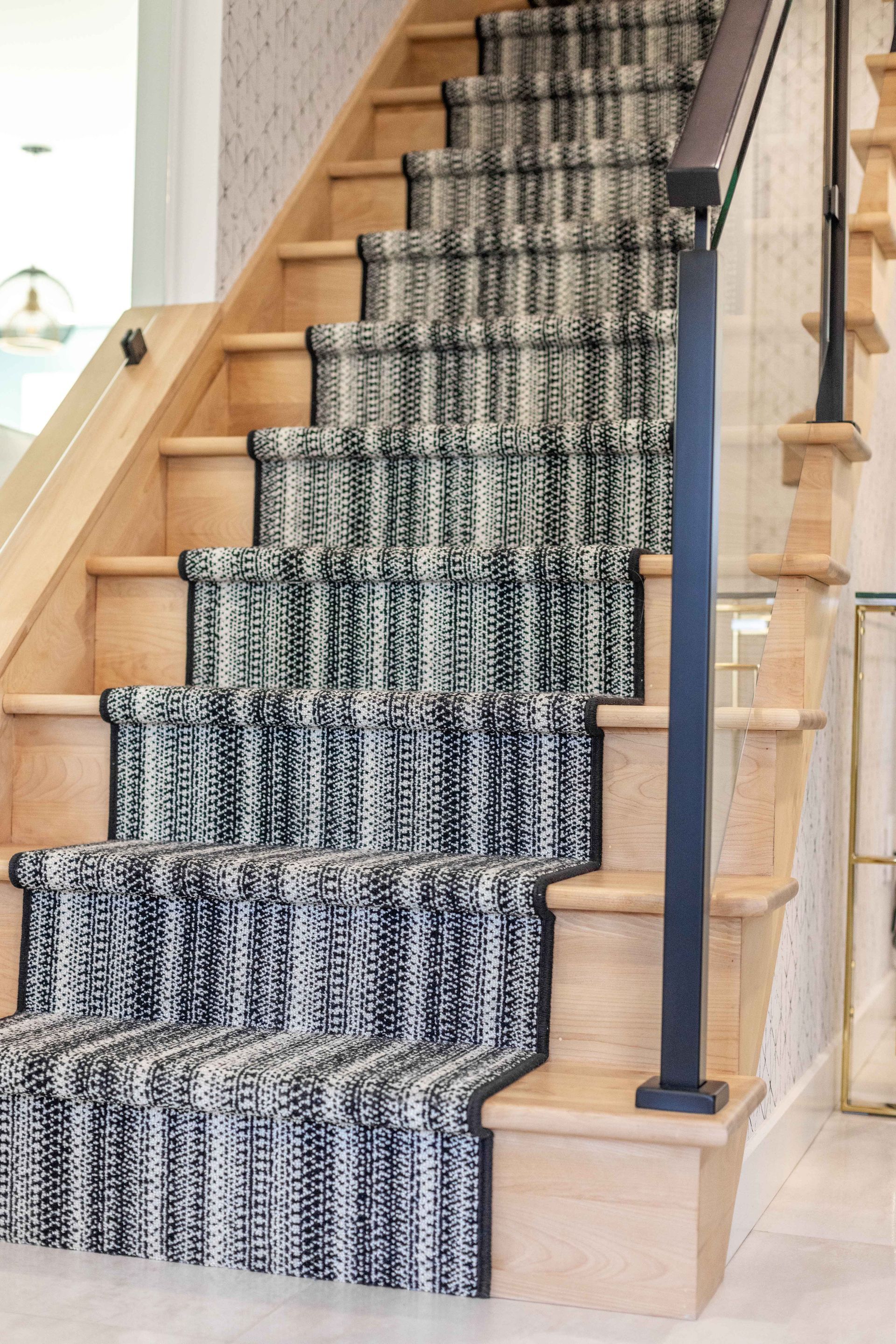 Escalier en bois avec tapis d'appoint à motifs noirs et blancs et rampe foncée.