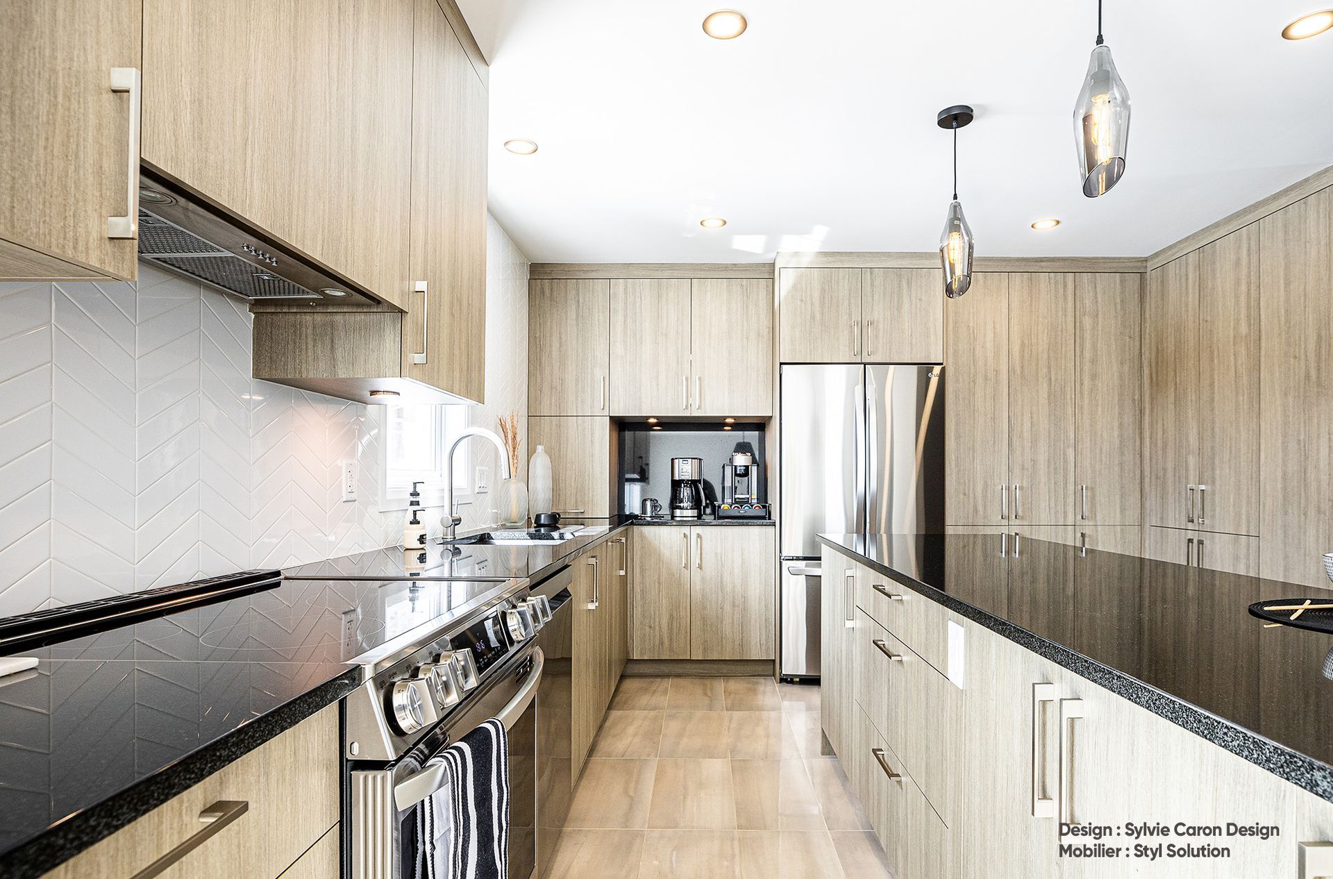 Cuisine moderne avec armoires en bois clair, appareils électroménagers en acier inoxydable et comptoirs foncés.