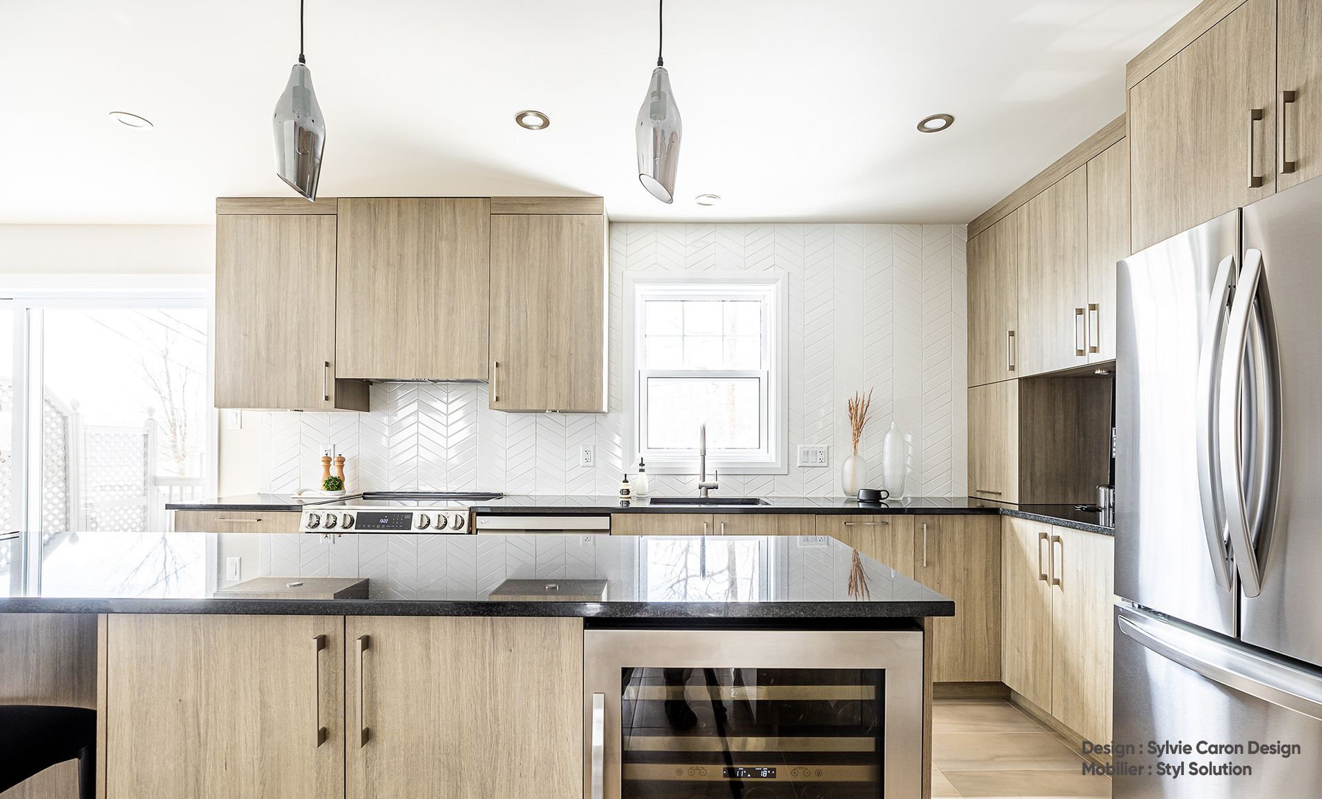 Cuisine moderne avec armoires en bois clair, appareils électroménagers en acier inoxydable et comptoirs foncés.