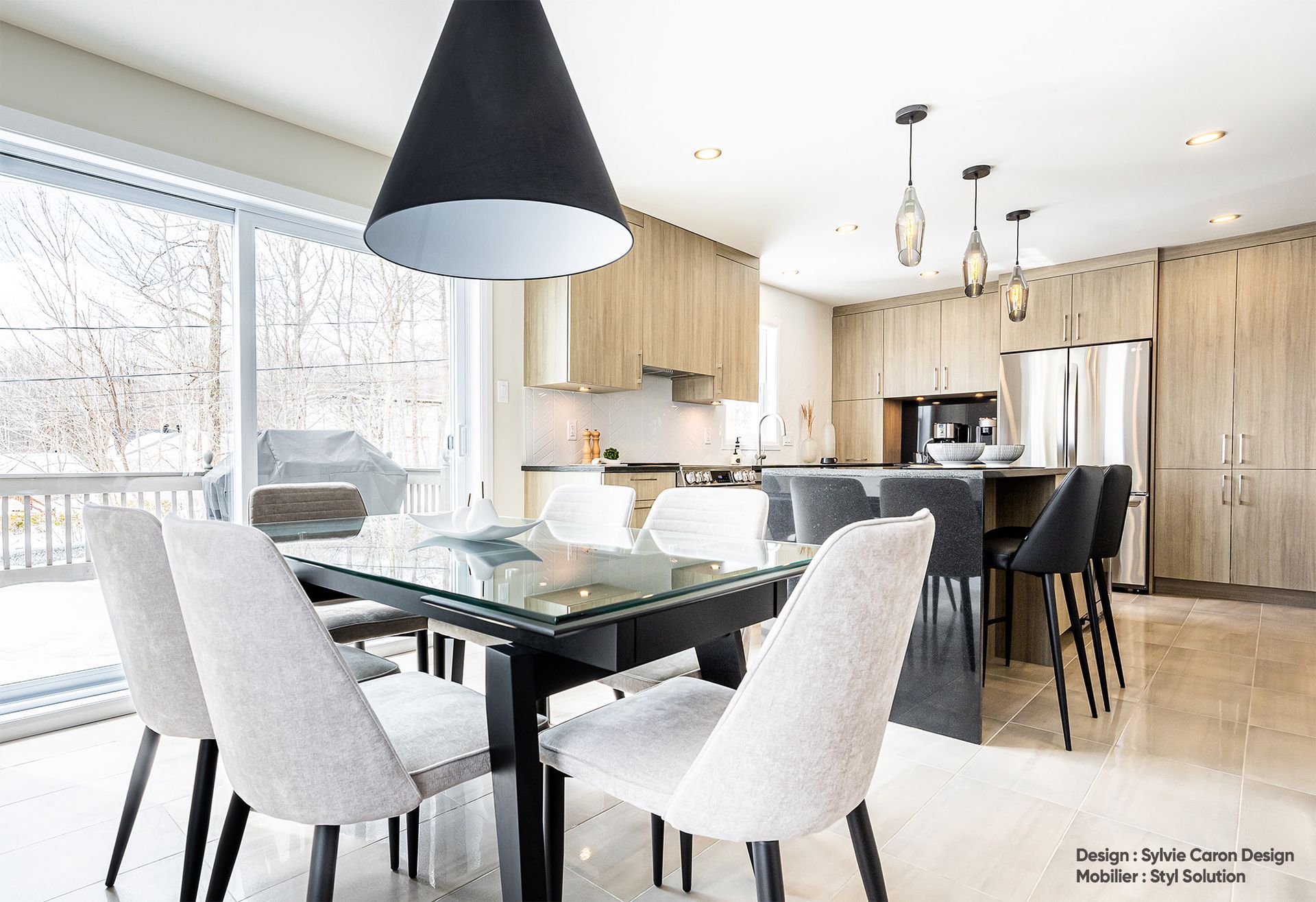 Cuisine et salle à manger modernes avec table en verre, chaises grises et meubles en bois clair.