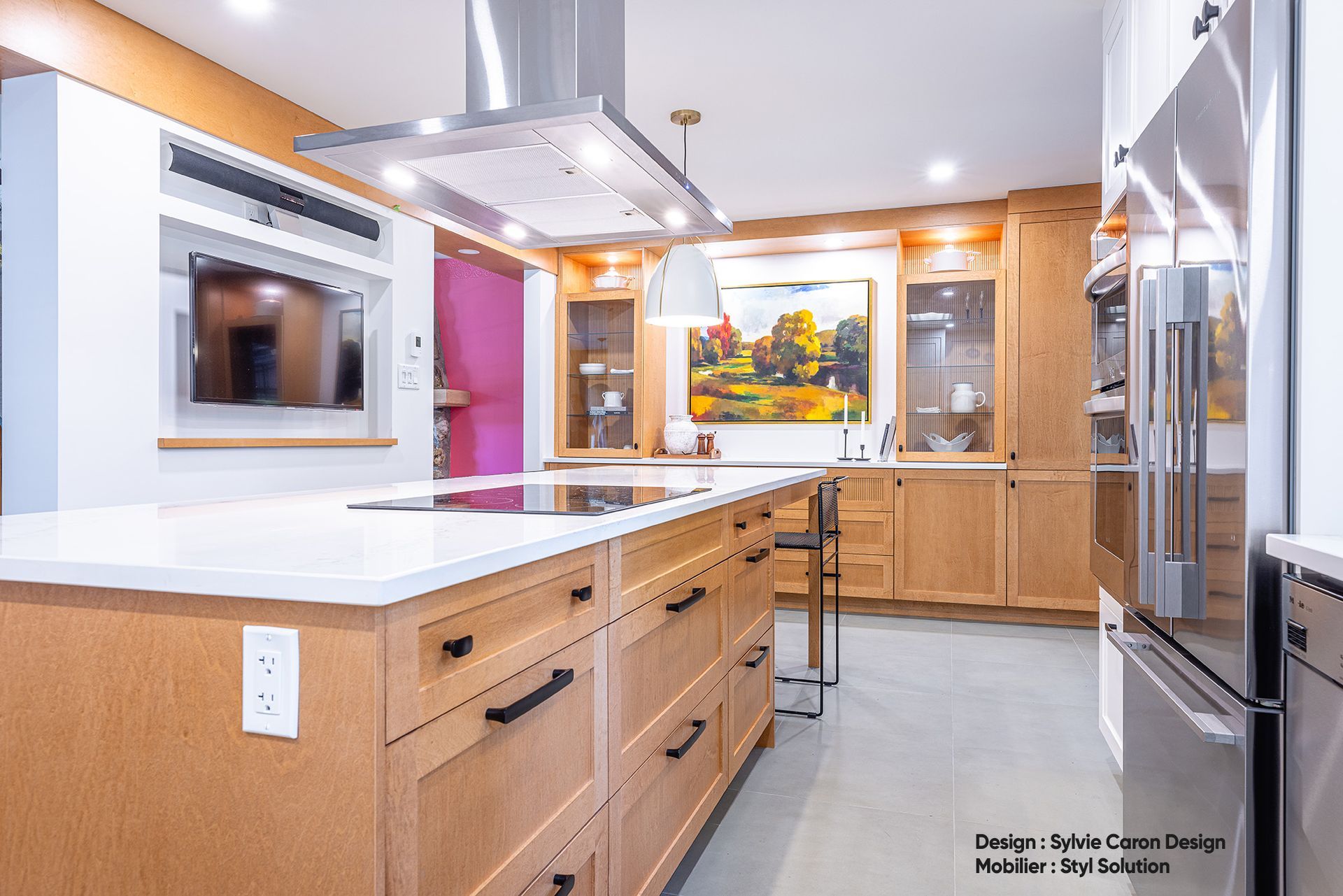 Cuisine moderne avec placards en bois, îlot central, appareils électroménagers en acier inoxydable et mur rose.
