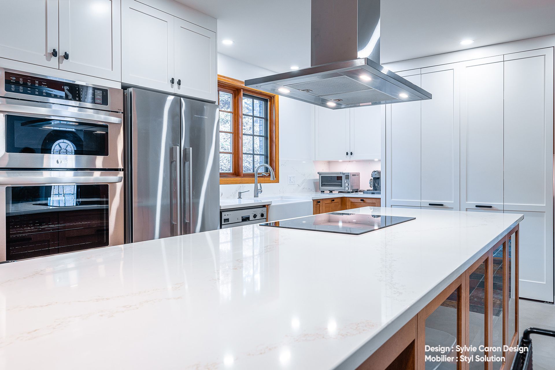 Cuisine blanche moderne avec appareils électroménagers en acier inoxydable, grand îlot avec plaque de cuisson