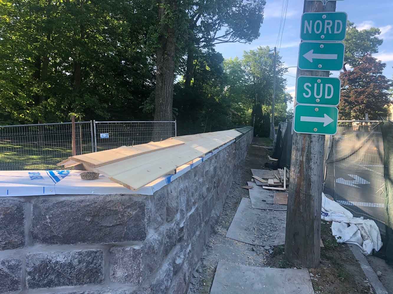 Mur en pierre avec lambris, panneaux de signalisation indiquant le nord et le sud par une journée ensoleillée.