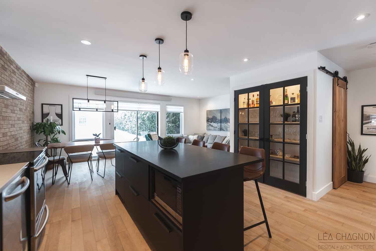 Cuisine moderne avec îlot central noir, parquet et placards vitrés.
