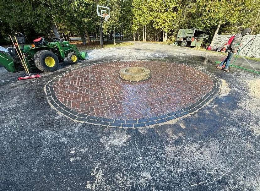 A tractor is parked in the middle of a driveway next to a fire pit.