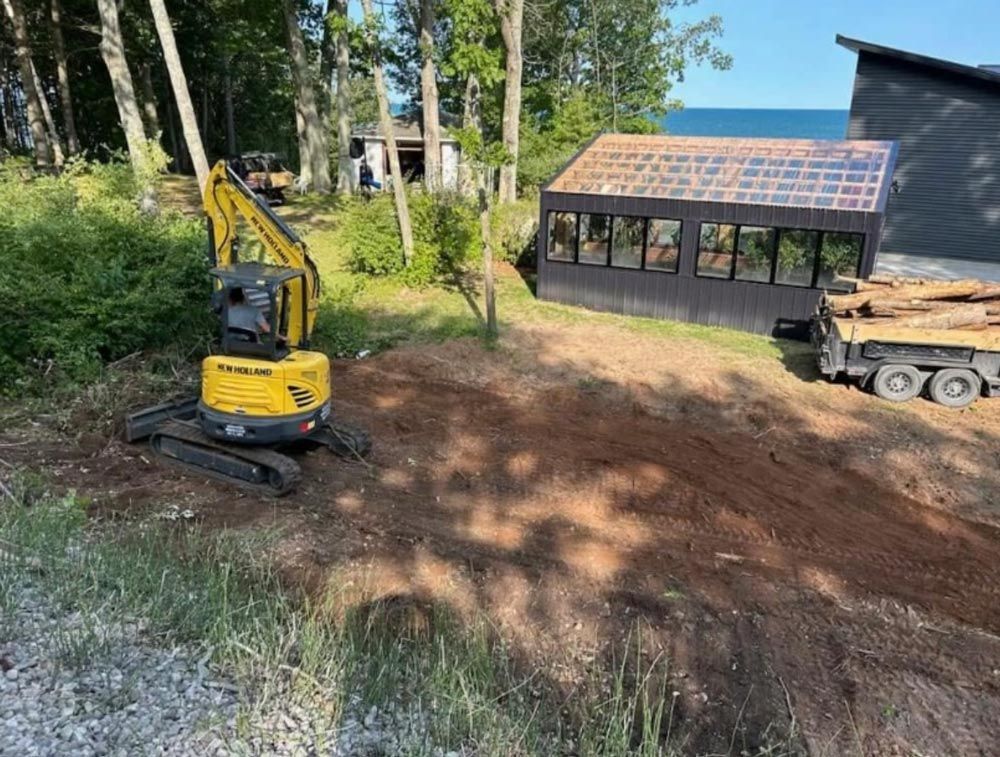 A small excavator is sitting in the dirt in front of a greenhouse.