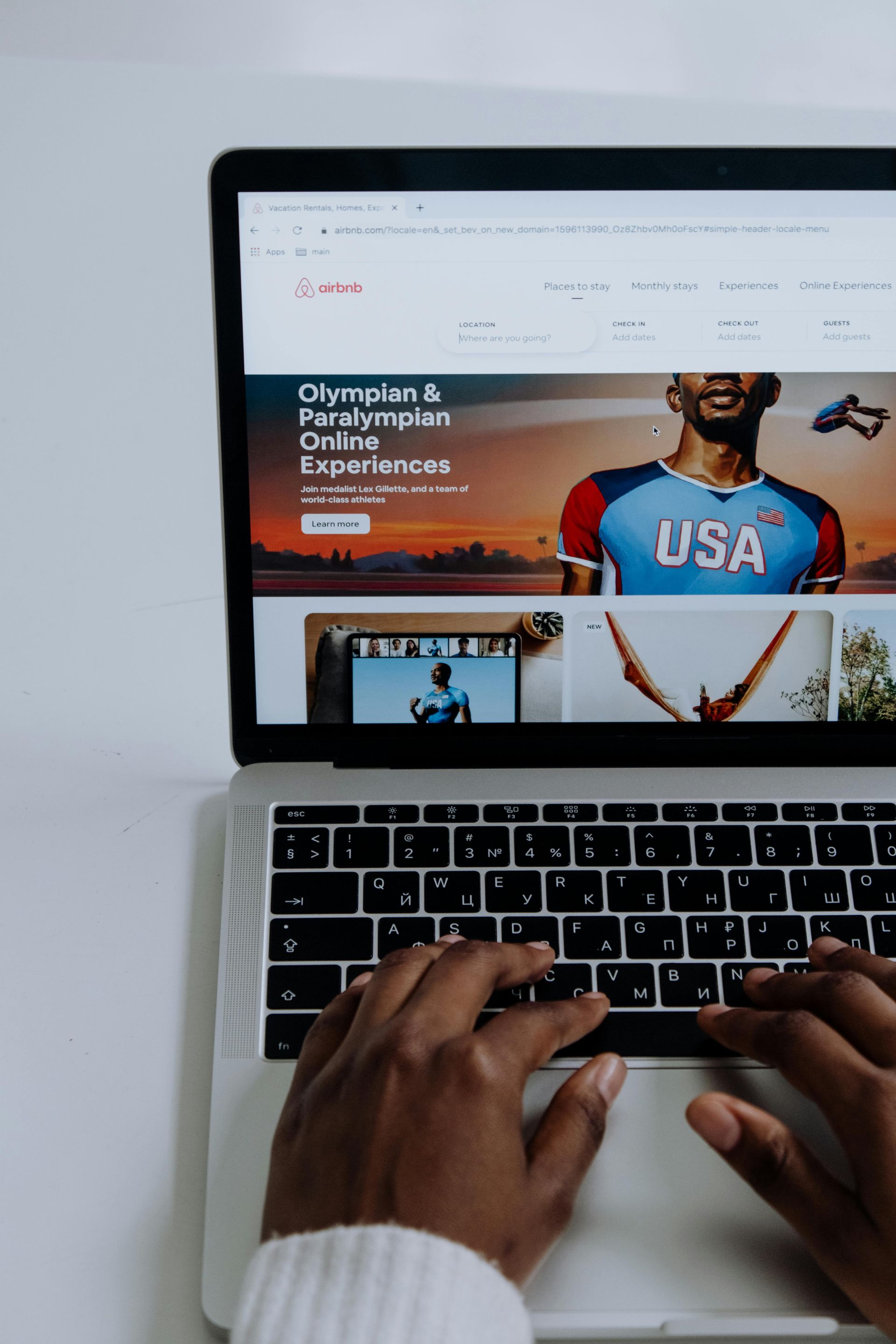 Person typing on a laptop with a website about the Olympics open.