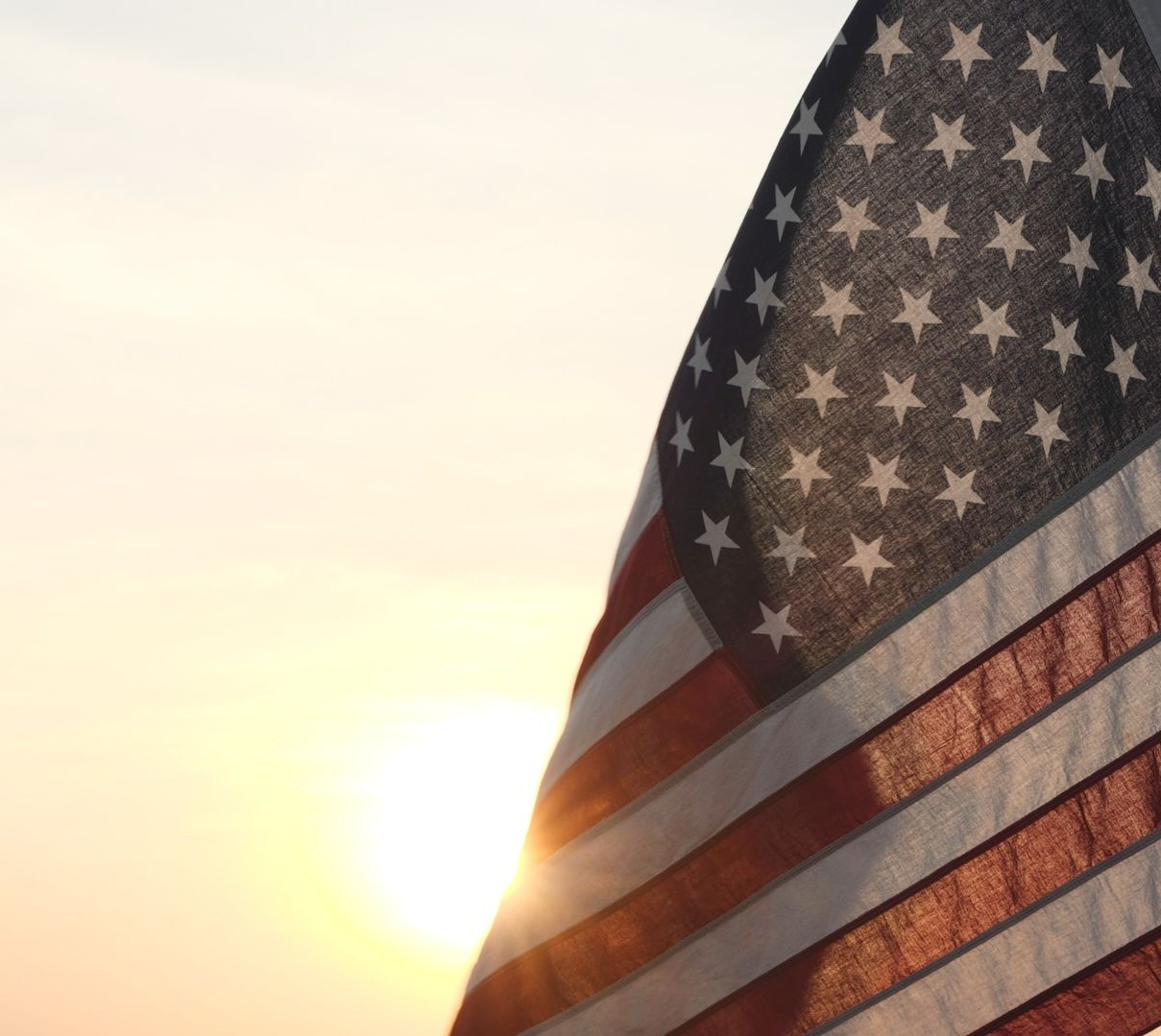 American flag backlit by the sun at sunset