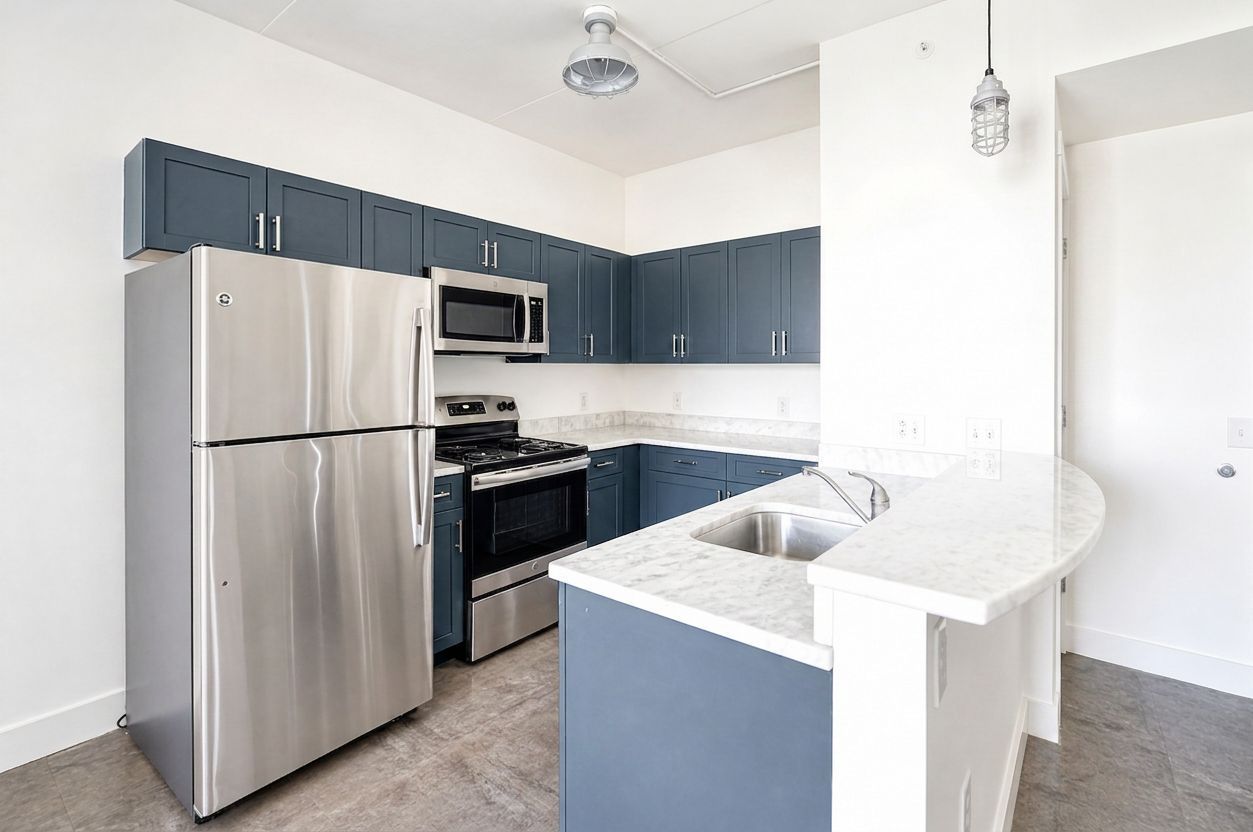 Modern kitchen with stainless steel appliances, blue cabinets, white island, and light gray tile floor