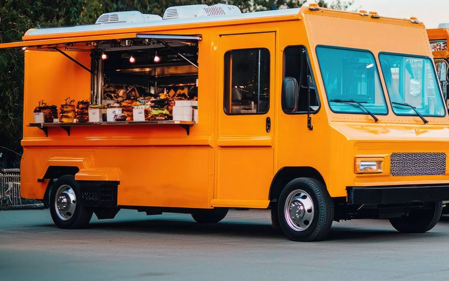 Bright orange food truck with serving window open and kitchen equipment inside
