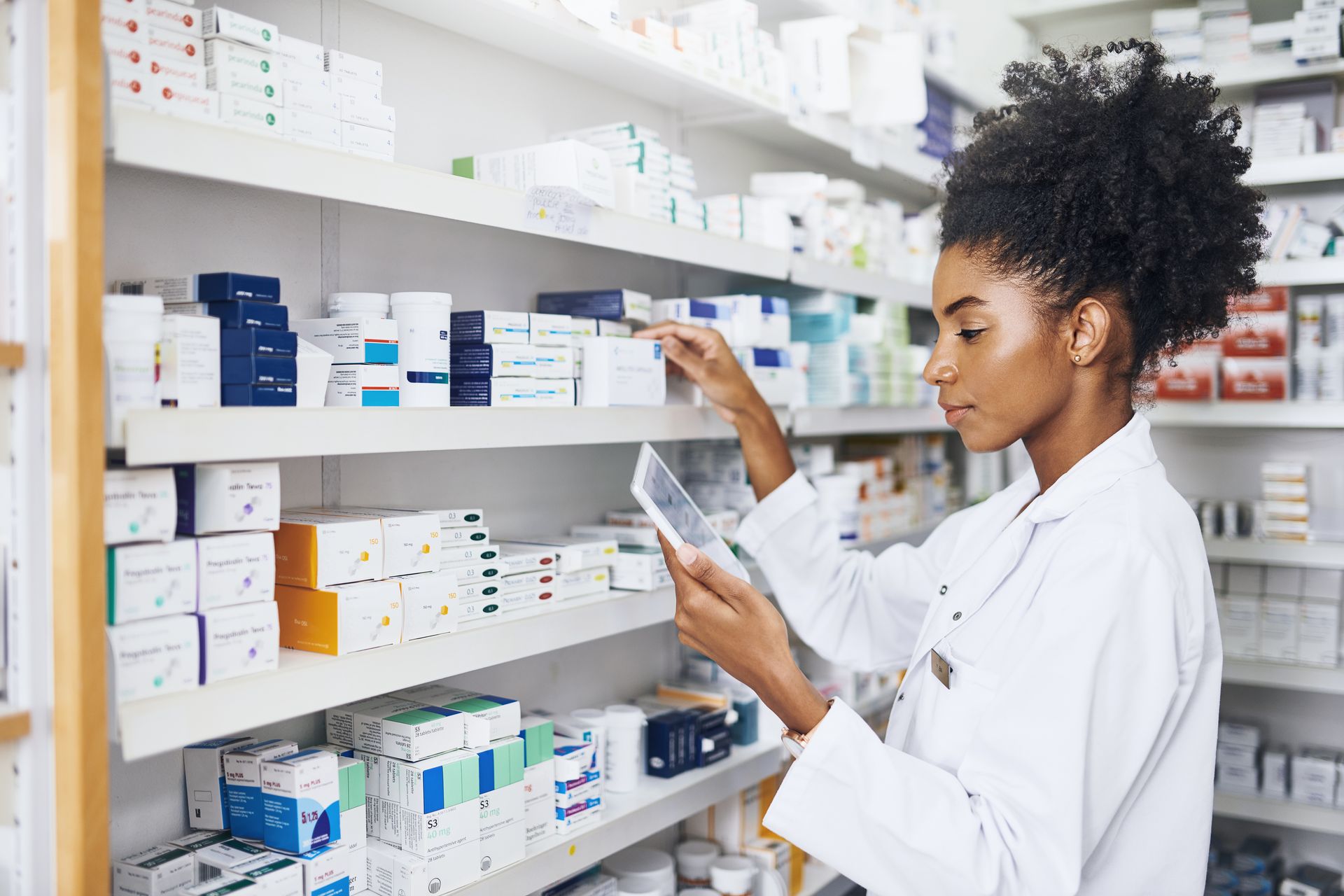 Pharmacist organizing medicine boxes on shelves in a pharmacy