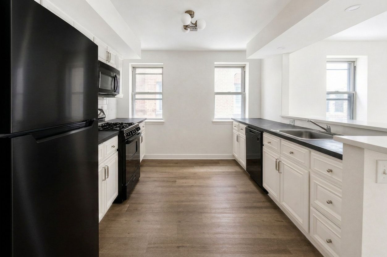 Modern kitchen with black refrigerator, white cabinets, wood floors, and three windows