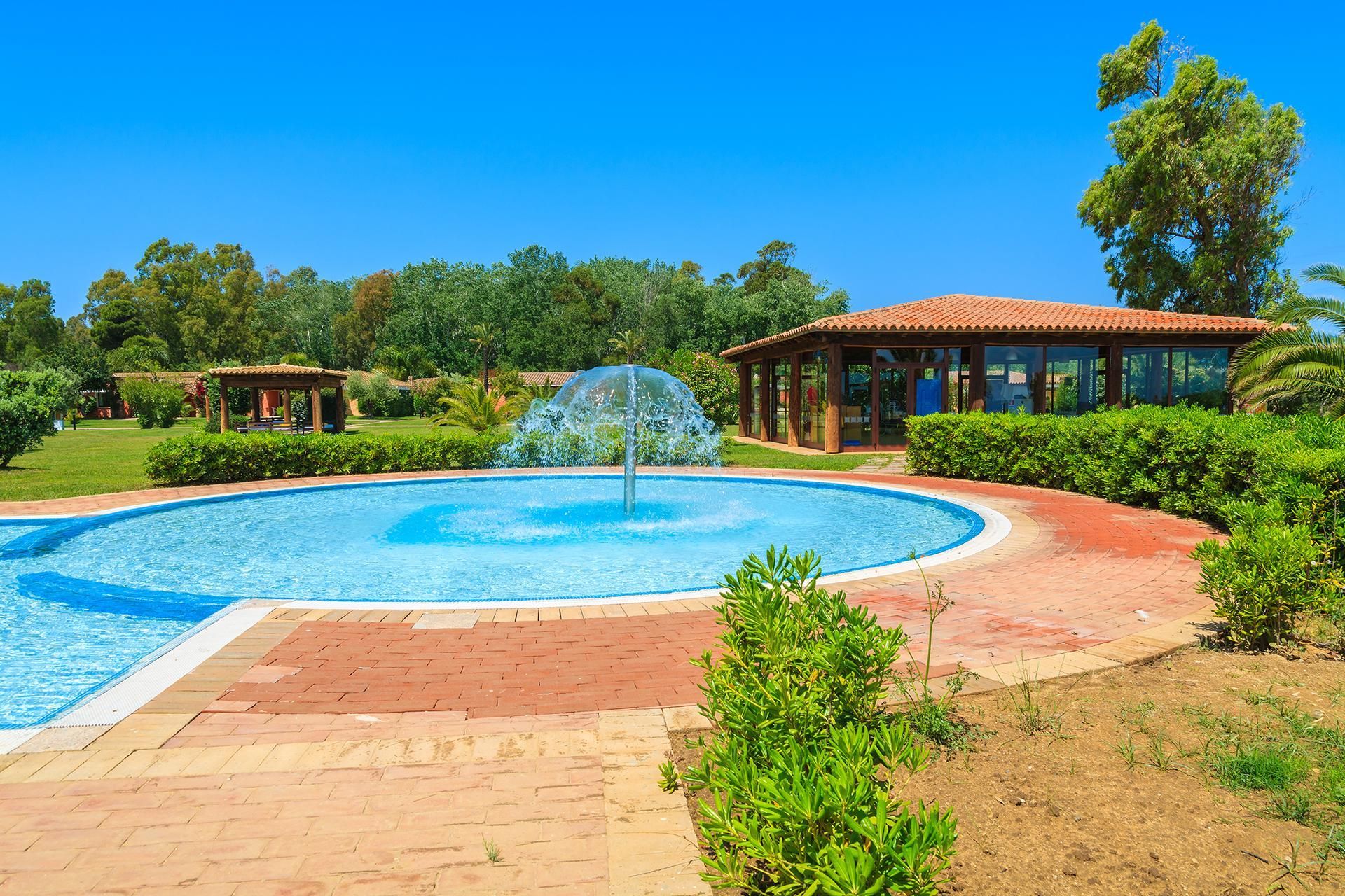 a large swimming pool with a fountain in the middle of it