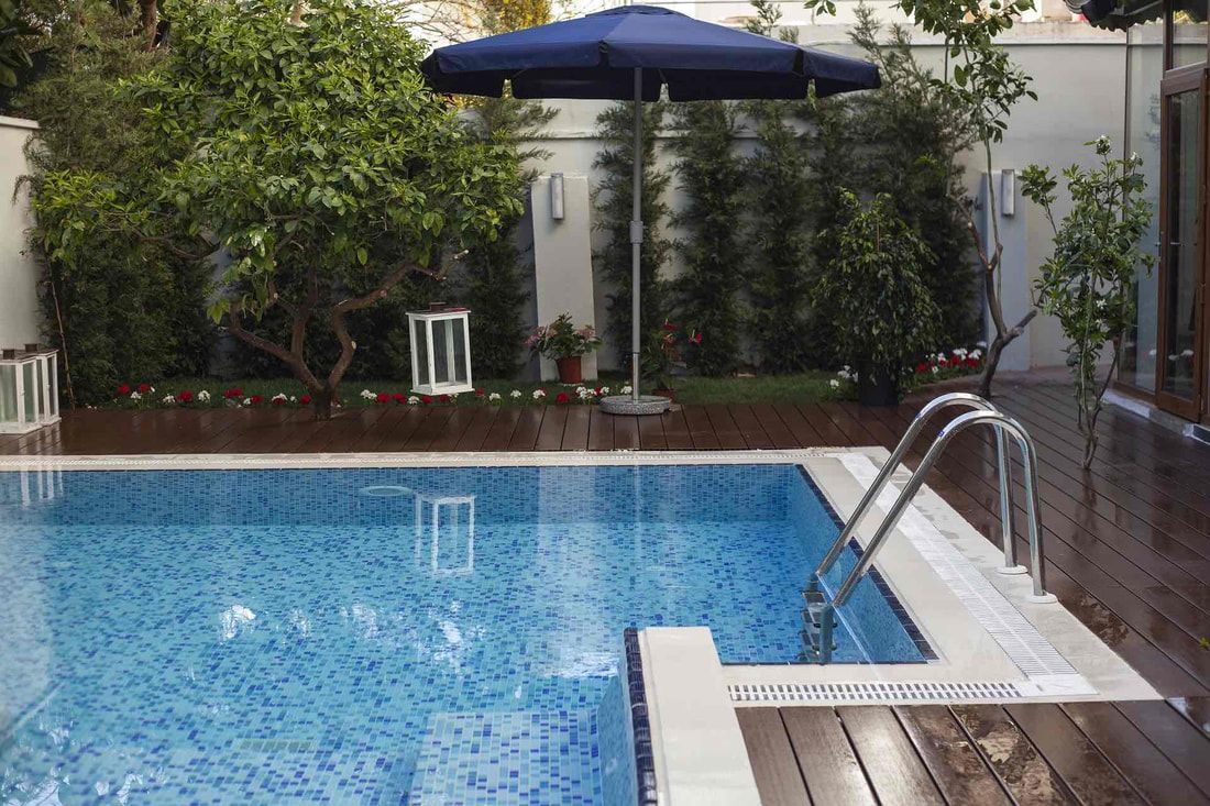 a large swimming pool with a blue umbrella in the background .