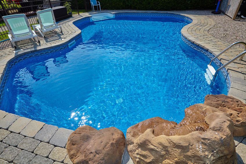 a large swimming pool with a rock in the middle of it .