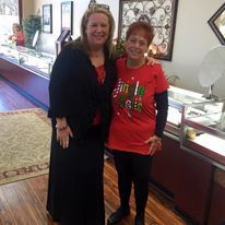 Two women are posing for a picture in a jewelry store.