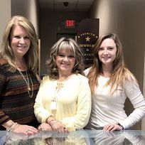 Three women are posing for a picture in a jewelry store.