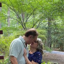 A man and a woman are kissing in the woods.