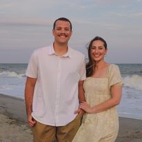 A man and a woman are posing for a picture on the beach.